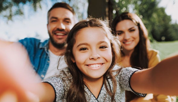 Familia sonriente en el parque mirando la cámara