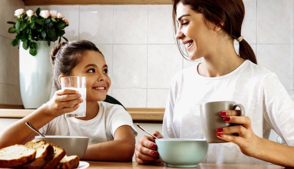 madre acompaña a su hija quien tiene un vaso con leche