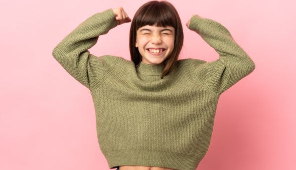 Una niña levanta los brazos como símbolo de su fuerza de voluntad