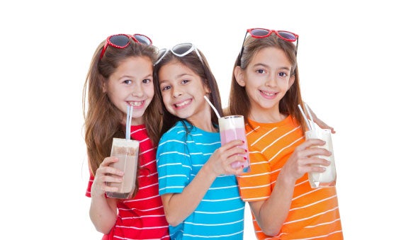 Tres niñas disfrutan sus vasos de leche de sabores