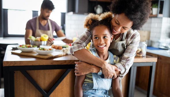 Una madre abraza a su hija mientras preparan alimentos en la cocina