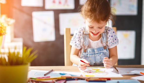 Una niña dibuja sus sueños y sonríe en la luz del sol