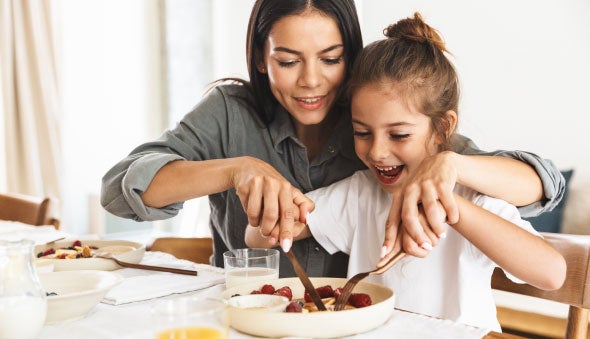 Mamá ayudando a comer a su hija