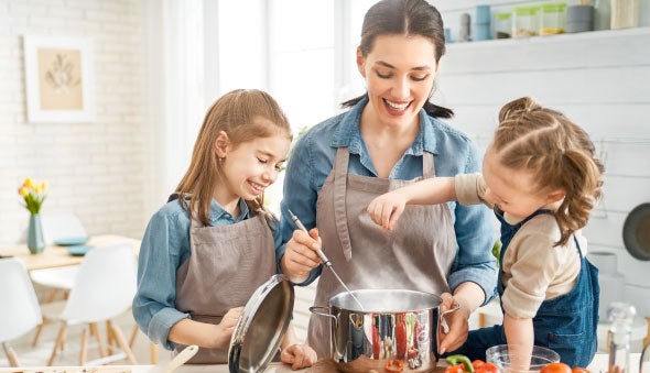 Mamá cocinando con sus dos hijas platos nutritivos