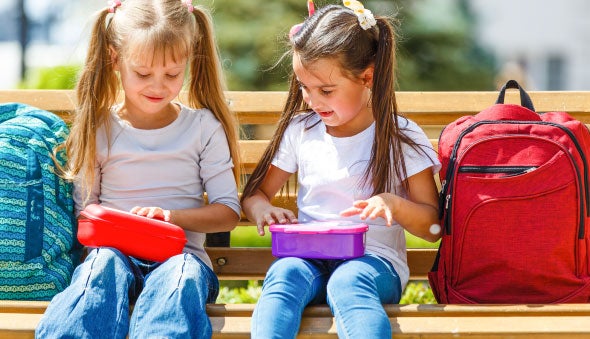 Niñas estudiantes destapando su lonchera