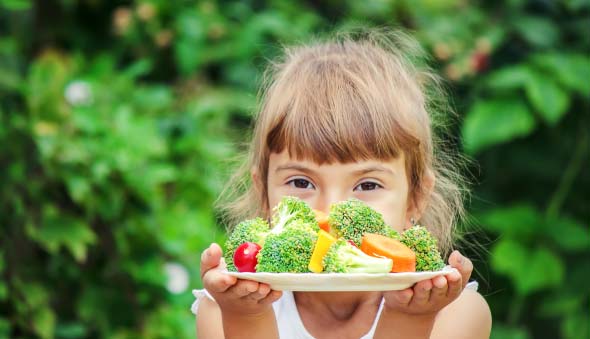 niña con plato de verduras