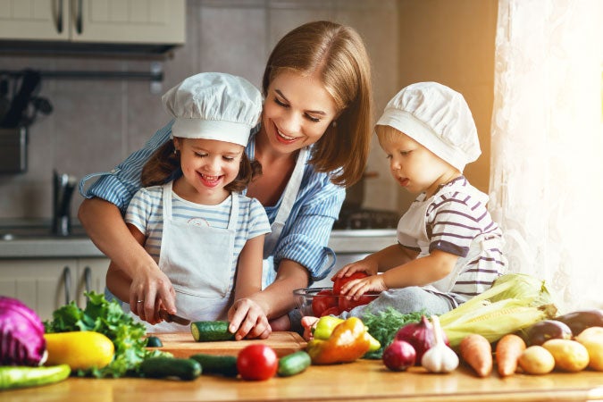 Mamá cocinando alegre con sus dos hijos